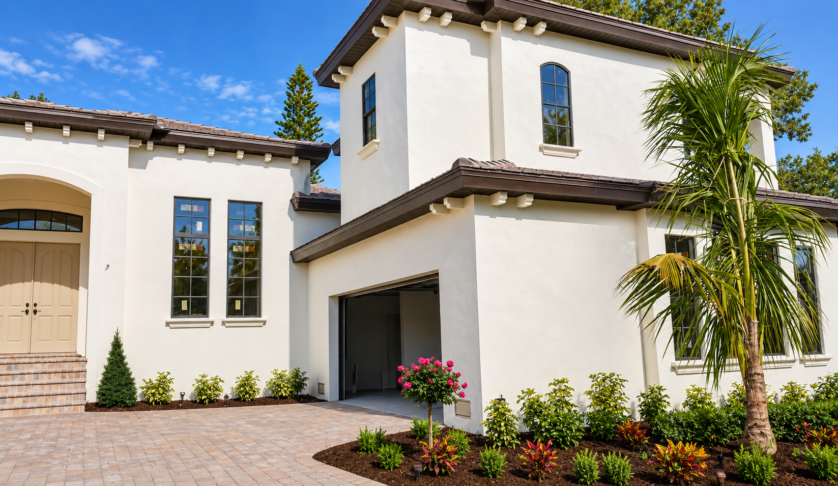 Two-story Mediterranean stucco home in Venice, FL with black-framed windows, tile roof, and paver driveway